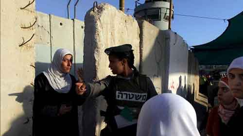 Una policía palestina indica el camino a una mujer palestina antes de cruzar el paso fronterizo de Kalandia hasta Jerusalén, en Cisjordania. EFE/Archivo