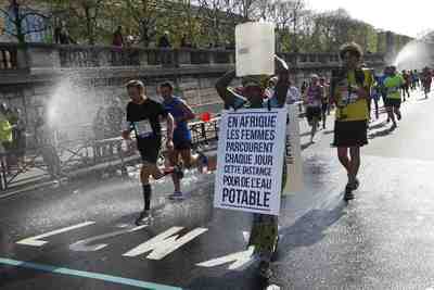 Una mujer africana con un cubo recorre el maratón de París